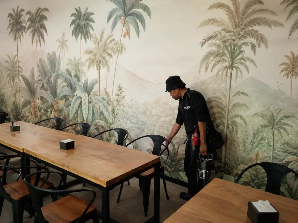 Pest control professional in protective suit inspecting for ant infestation inside a Malaysian home